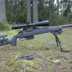 En prickskyttegevär med kikarsikte och bipod ligger i skogen. Artikeln handlar om vad man får jaga med 22lr.