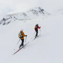 Två skidåkare på väg uppför ett snötäckt berg, en fantastisk sylarna topptur i fjällen.