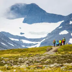 Vandrare på väg mot STF Sylarna, med glaciärklädda berg i bakgrunden.