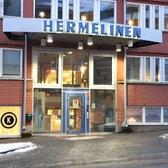 Byggnaden "HERMELINEN" med stora fönster och tegelväggar. En skylt med "Fotvård" syns. Trots namnet är denna hermelin inte farlig, bara en byggnad.
