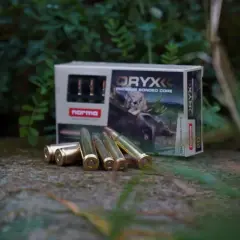 Norma Oryx ammunition, med olika vapen namn på förpackningen, ligger utspridda på en sten.