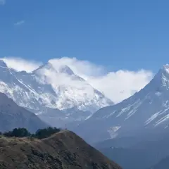 Majestätiska snöklädda bergstoppar i Nepal, med en kulle i förgrunden. En dröm om att vandra i Nepal.