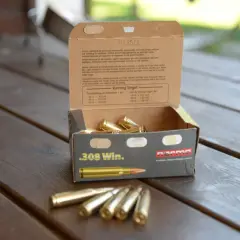 En öppen ask med .308 Win. ammunition på ett träbord. Texten på asken ger information om hur mycket ammunition man får ha hemma och dess användning.