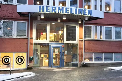 Byggnaden "HERMELINEN" med stora fönster och tegelväggar. En skylt med "Fotvård" syns. Trots namnet är denna hermelin inte farlig, bara en byggnad.