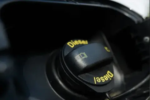 En svart tanklock med texten "Diesel" i gult. Symbolen för en öppen bok indikerar att man ska läsa instruktionerna innan man lagra diesel.
