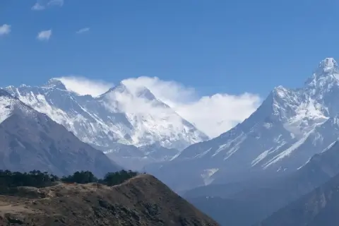 Majestätiska snöklädda bergstoppar i Nepal, med en kulle i förgrunden. En dröm om att vandra i Nepal.