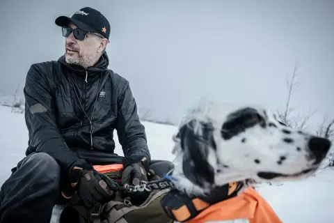 Man med hund i snölandskap, kanske på en resa genom girjas sameby.