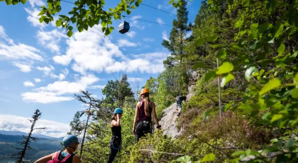Äventyr vid Ramundberget: klättrare på klippvägg, linbana i skyn, en perfekt dag för vandring och utmaningar.