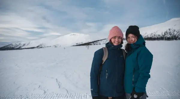 Två glada vandrare på vintern i snöklädda fjäll.