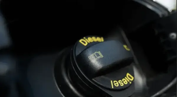 En svart tanklock med texten "Diesel" i gult. Symbolen för en öppen bok indikerar att man ska läsa instruktionerna innan man lagra diesel.