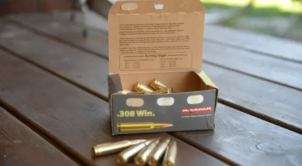 En öppen ask med .308 Win. ammunition på ett träbord. Texten på asken ger information om hur mycket ammunition man får ha hemma och dess användning.