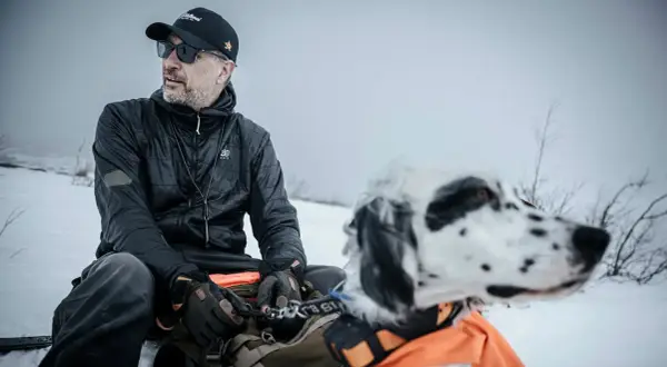 Man med hund i snölandskap, kanske på en resa genom girjas sameby.