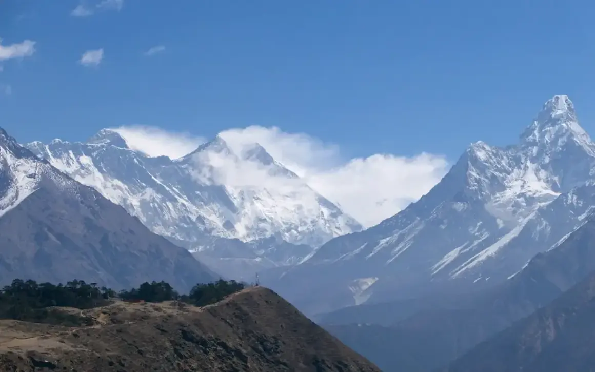 Majestätiska snöklädda bergstoppar i Nepal, med en kulle i förgrunden. En dröm om att vandra i Nepal.