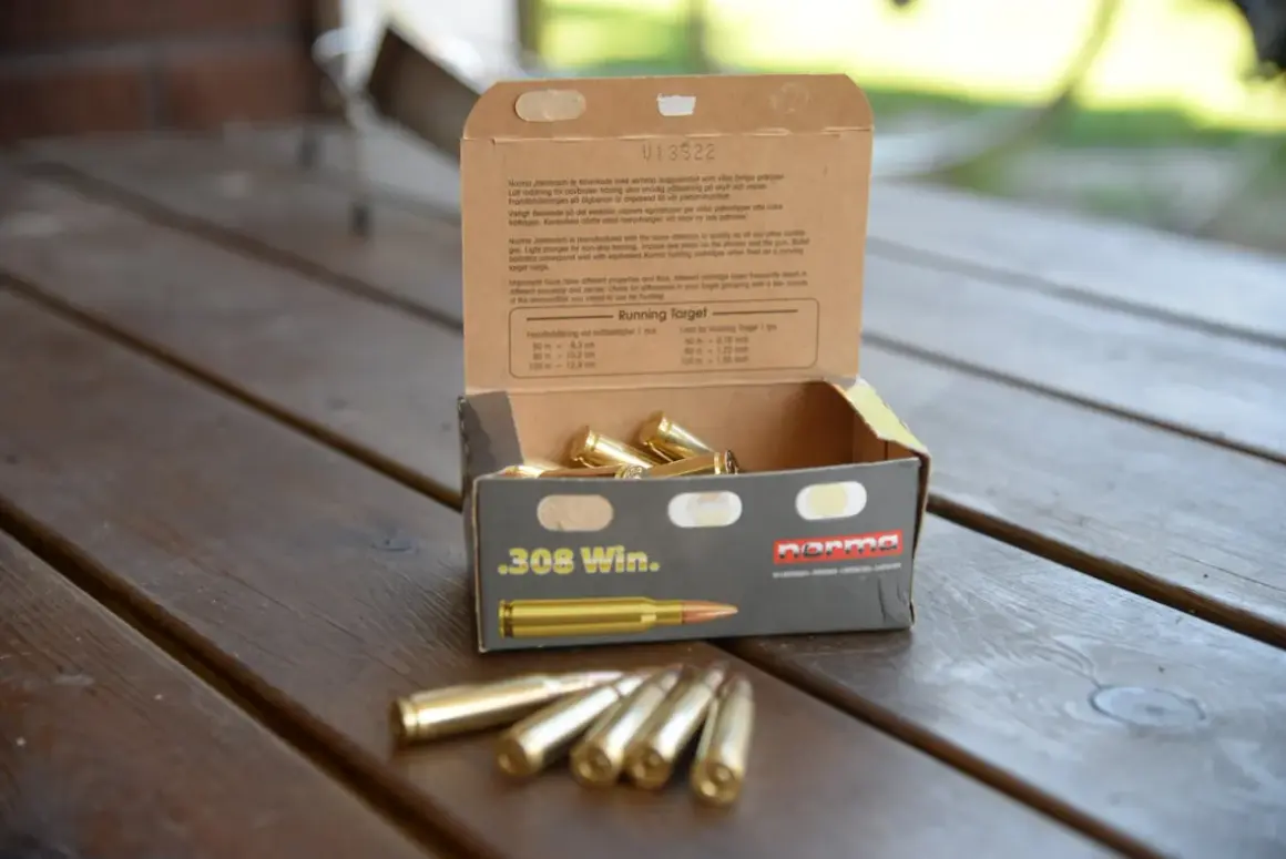 En öppen ask med .308 Win. ammunition på ett träbord. Texten på asken ger information om hur mycket ammunition man får ha hemma och dess användning.