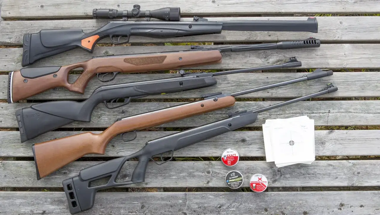 En samling kraftiga luftvapen, ammunition och m&aring;ltavlor ligger utspridda p&aring; en tr&auml;b&auml;nk.