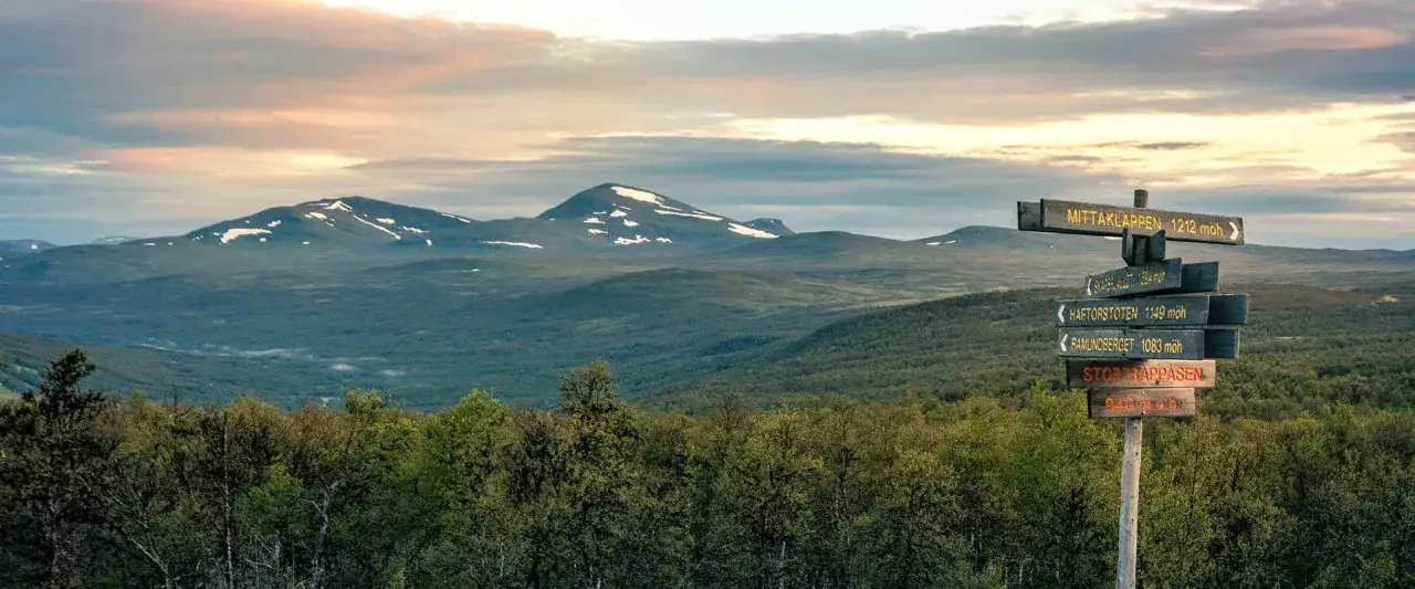 Vandring Ramundberget: en skylt visar v&auml;gen mot toppar med sn&ouml;. Vackert landskap i J&auml;mtland.