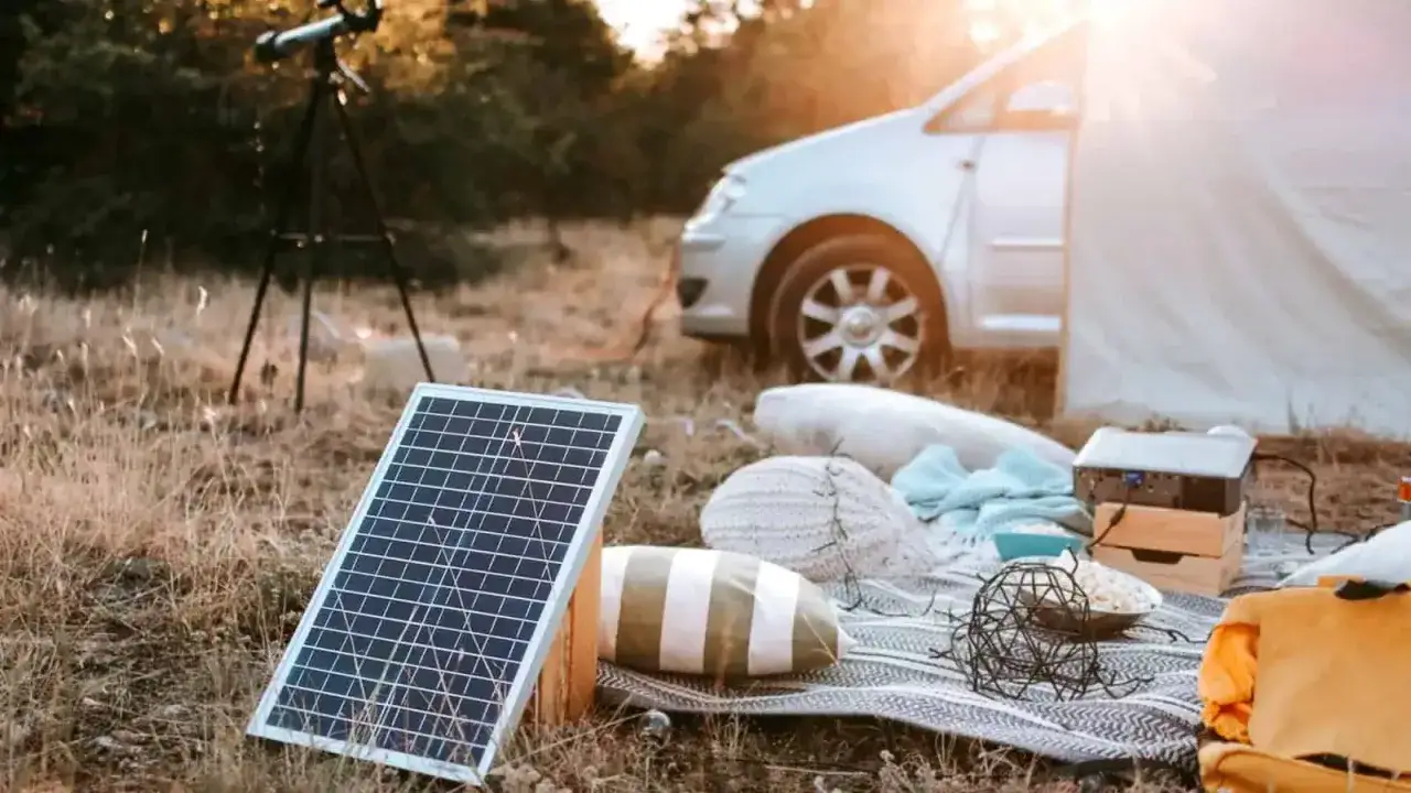 Bärbara solceller laddar utrustning vid en campingplats med husbil och tält.