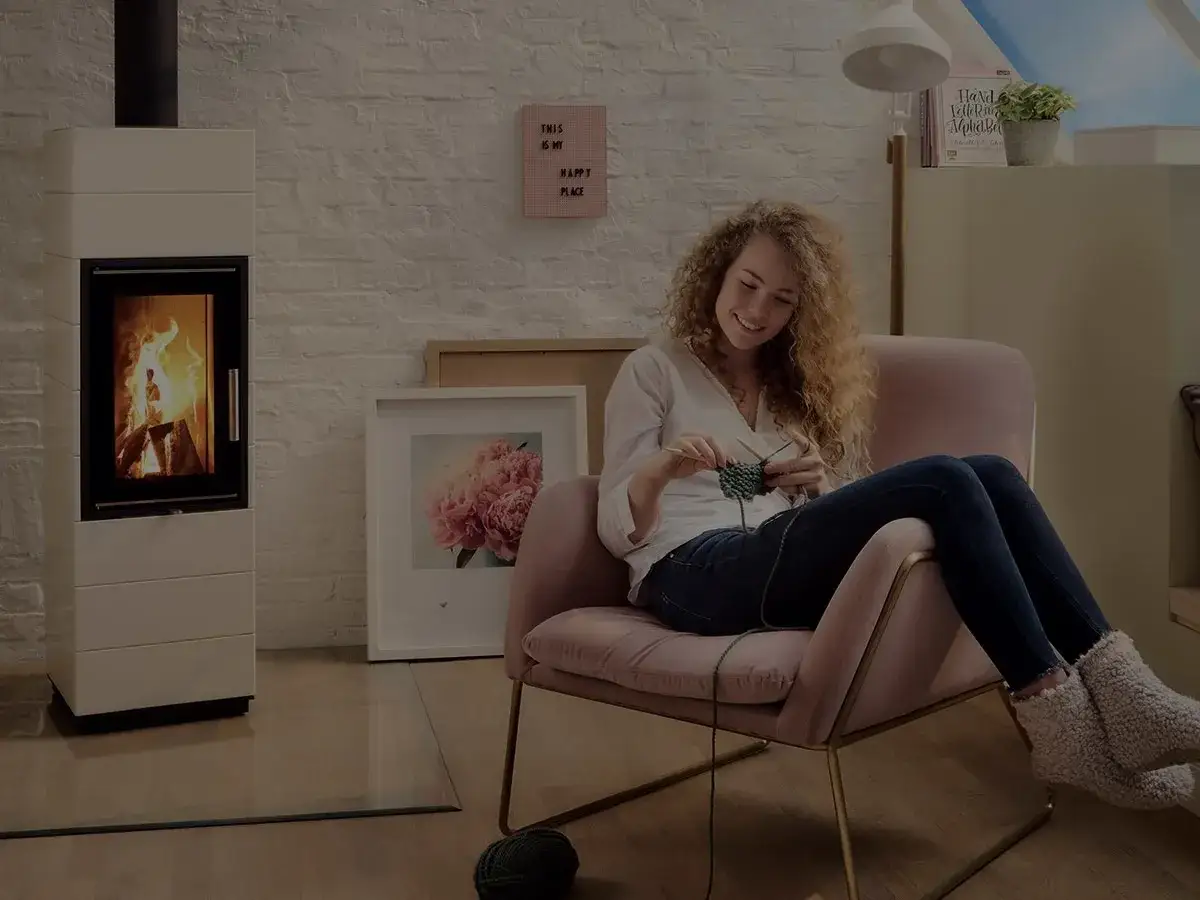 En kvinna stickar i en mysig fåtölj framför en sprakande sprit kamin.