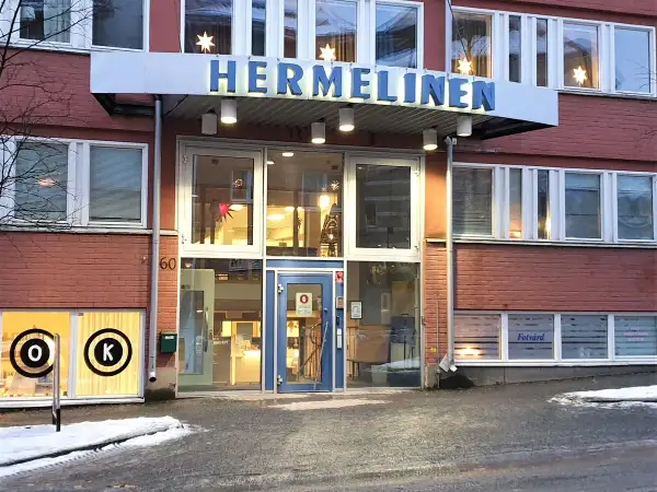 Byggnaden "HERMELINEN" med stora fönster och tegelväggar. En skylt med "Fotvård" syns. Trots namnet är denna hermelin inte farlig, bara en byggnad.
