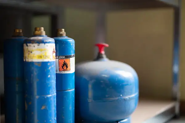 Blå gasflaskor, en med varningssymbol för brandfarlighet, redo att förvara bensin säkert.