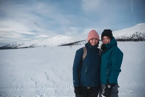 Två glada vandrare på vintern i snöklädda fjäll.