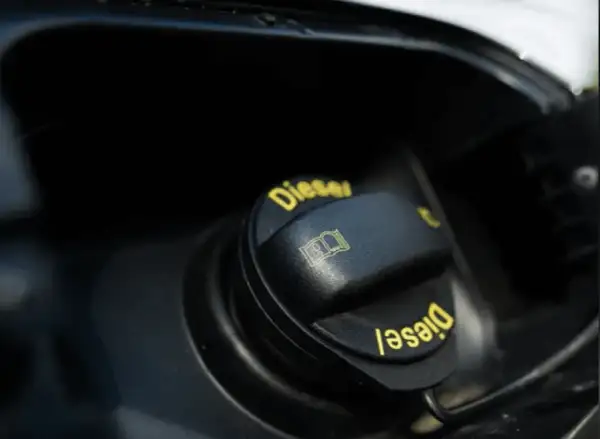En svart tanklock med texten "Diesel" i gult. Symbolen för en öppen bok indikerar att man ska läsa instruktionerna innan man lagra diesel.