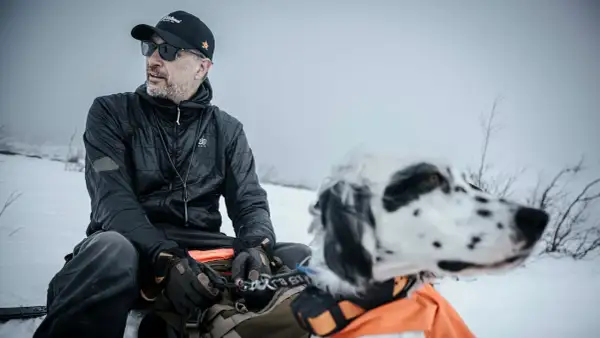 Man med hund i snölandskap, kanske på en resa genom girjas sameby.